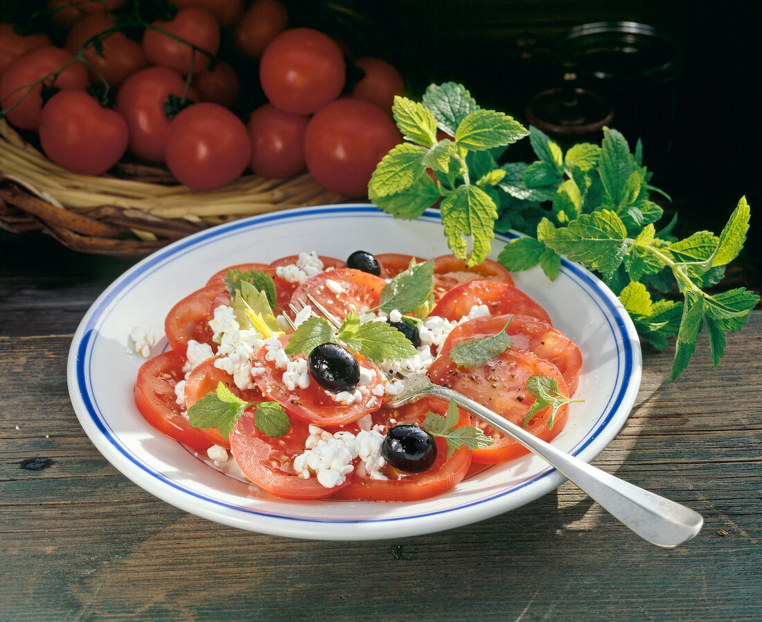 Tomatoes with cream cheese, olives and lemon balm on plate