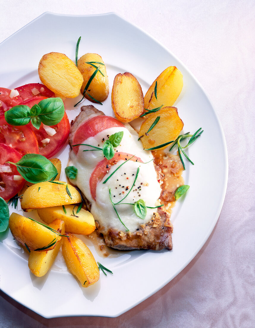 Mit Mozzarella und Tomaten überback- enes Schnitzel m. Rosmarinkartoffeln