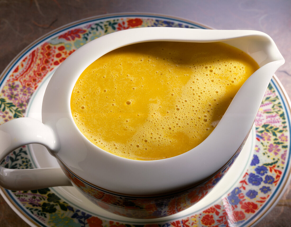 Curry sauce with peppers in ceramic gravy boat kept on plate