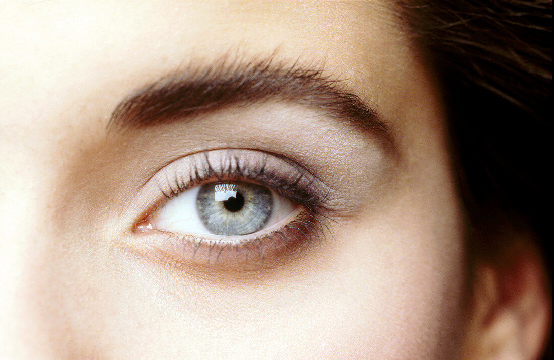 Extreme close-up of blue eyed woman wearing gray eye shadow