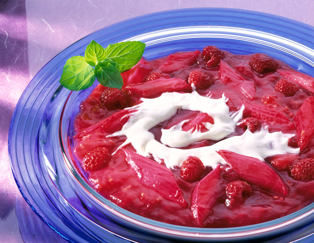 Rhubarb and raspberry compote with mint leaves in glass serving dish