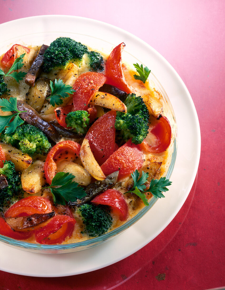 Bowl of tomato gratin with poultry liver, broccoli, potatoes and onions on plate