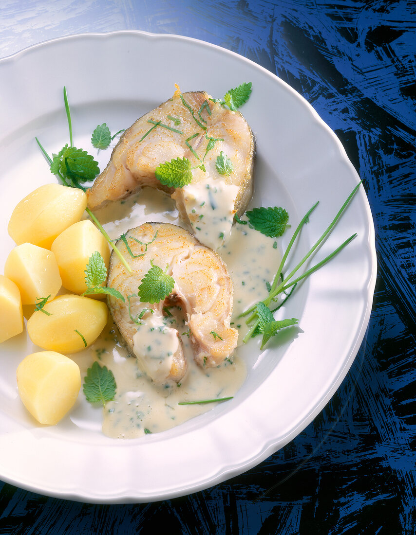 Cod loin with herb sauce served with potatoes on dish