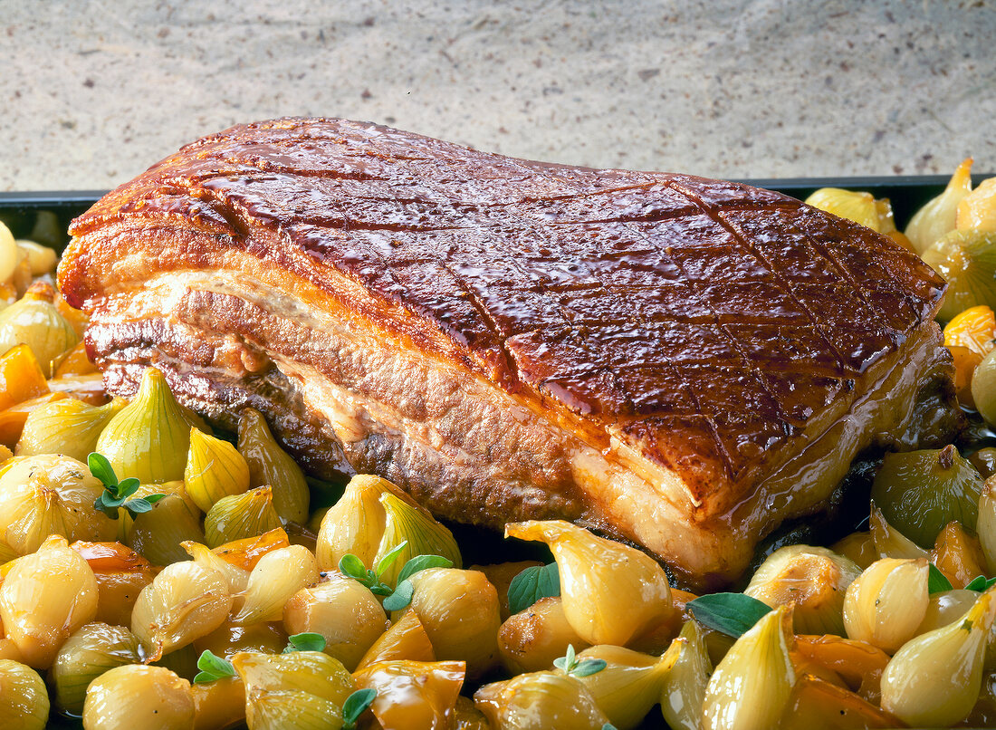 Close-up of roasted pork belly with shallots