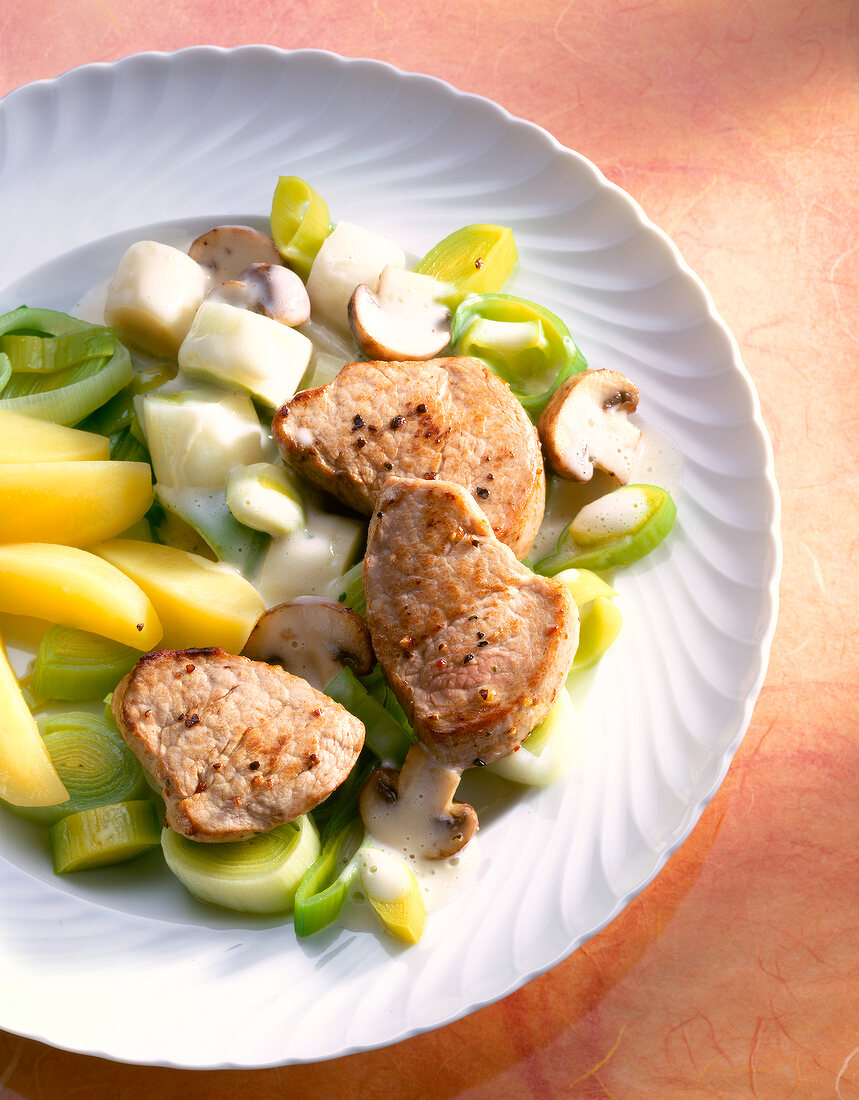 Medallions on leek vegetables, served with boiled potatoes on plate