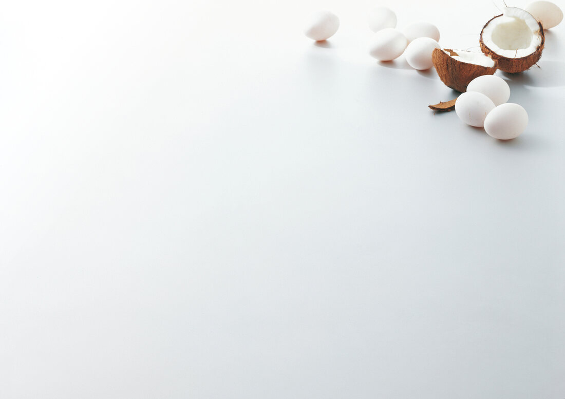 Eggs and halved coconut on white background