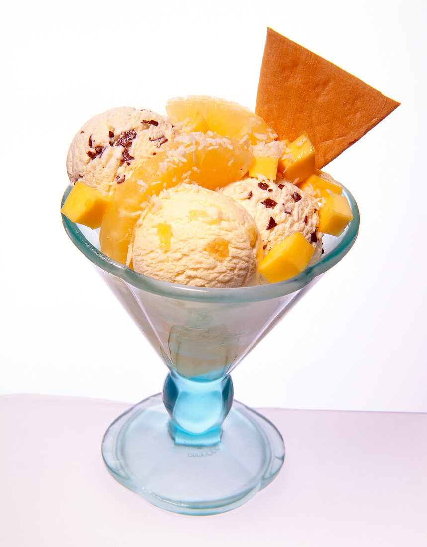 Scoops of ice cream with mango and pineapple pulp and sundae cone
