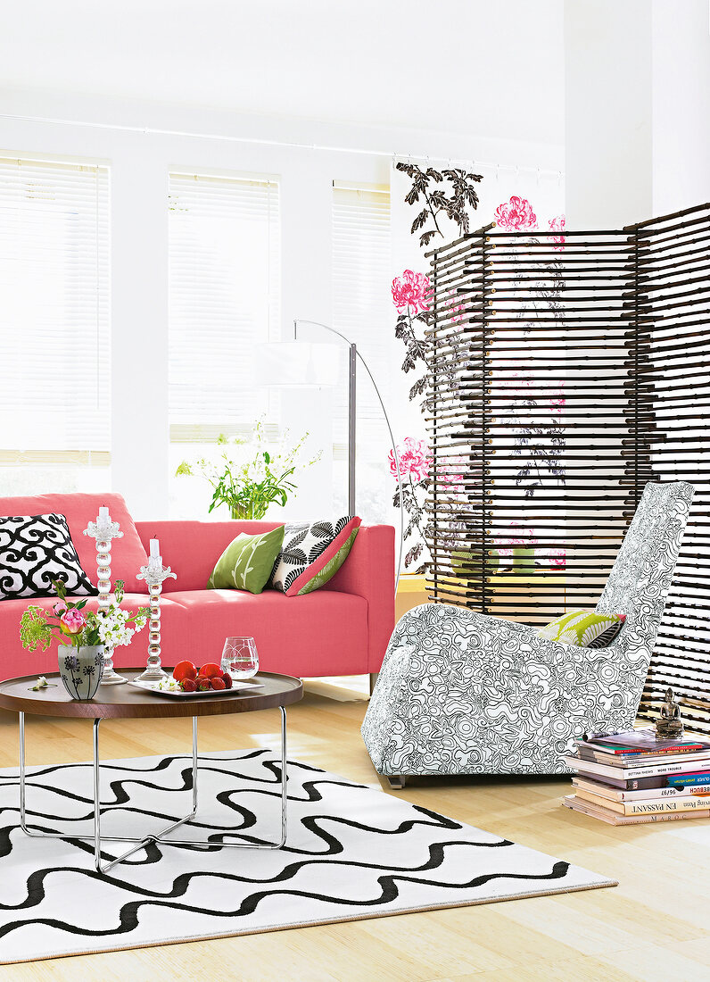 Wohnzimmer in schwarz weiß mit rosa Sofa und Bambus Paravent