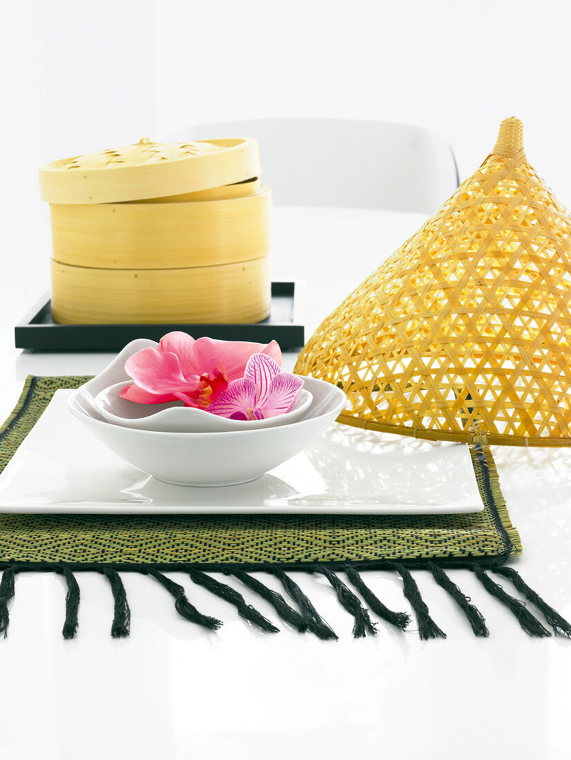 Bowl of orchids flower with bamboo basket on table