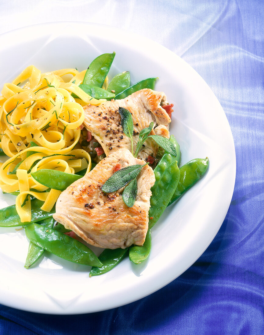 Close-up of stuffed turkey escalopes, ribbon noodles and sugar peas in dish