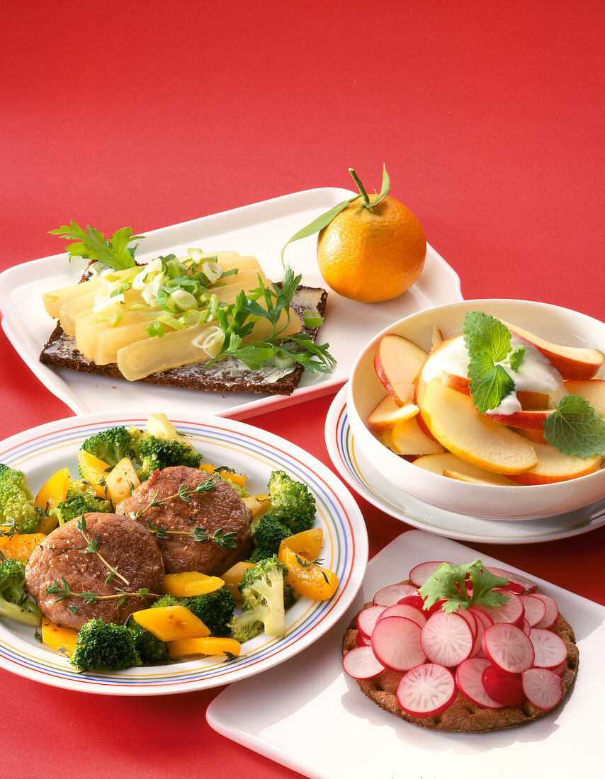 Close-up of pork with vegetables, cheese bread, apple slices, bread and radish