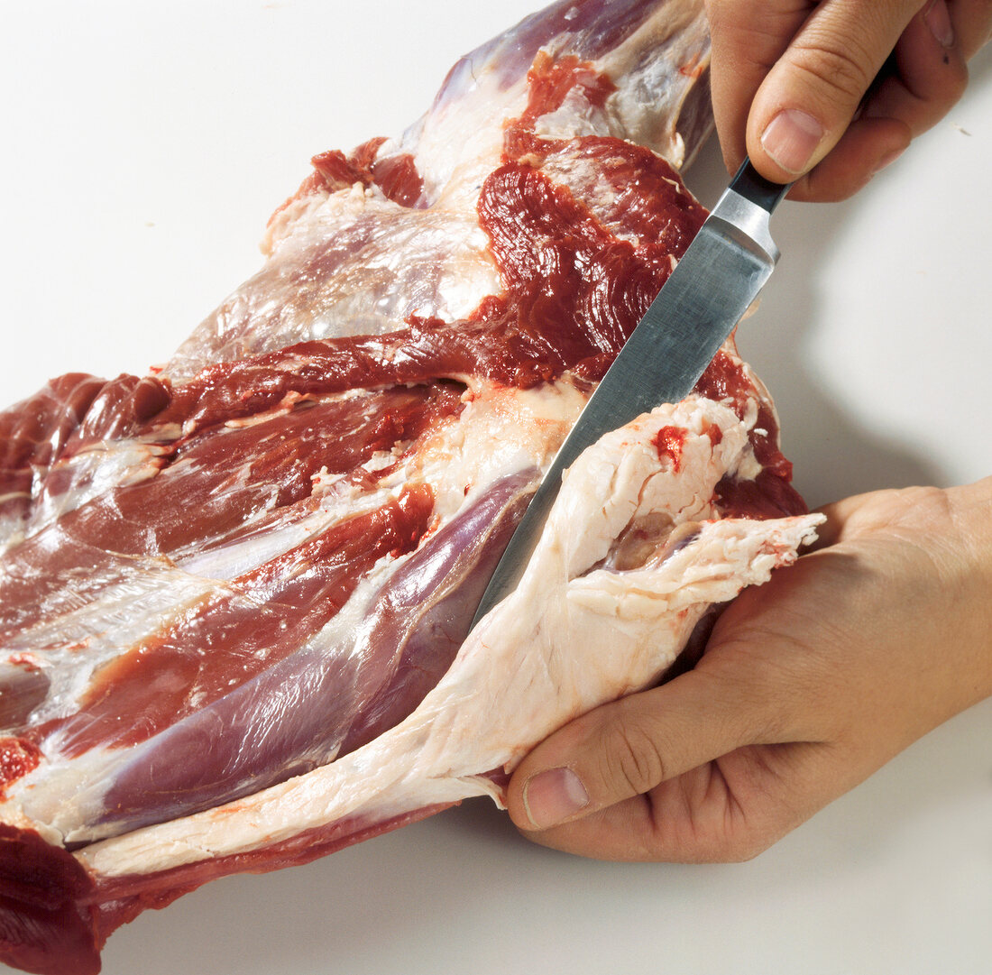 Hand removing fat from meat