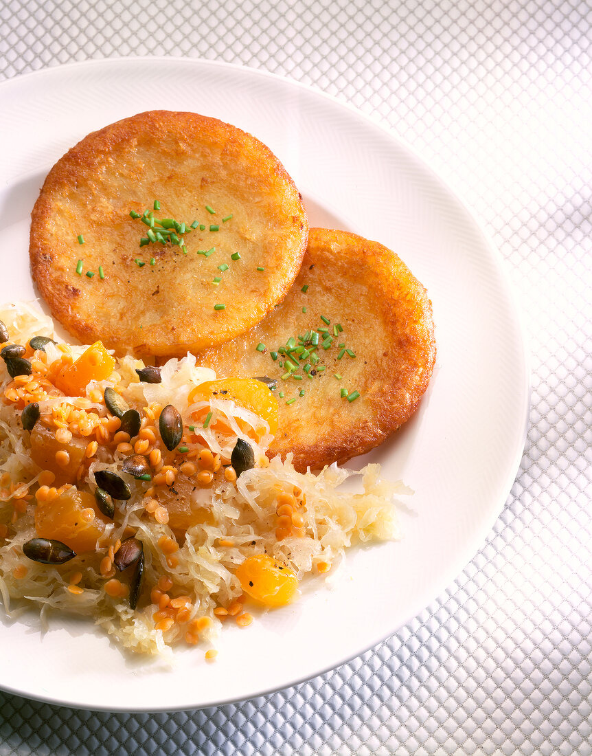 Close-up of sauerkraut with red lentils, potato pancakes and pumpkin cubes in dish