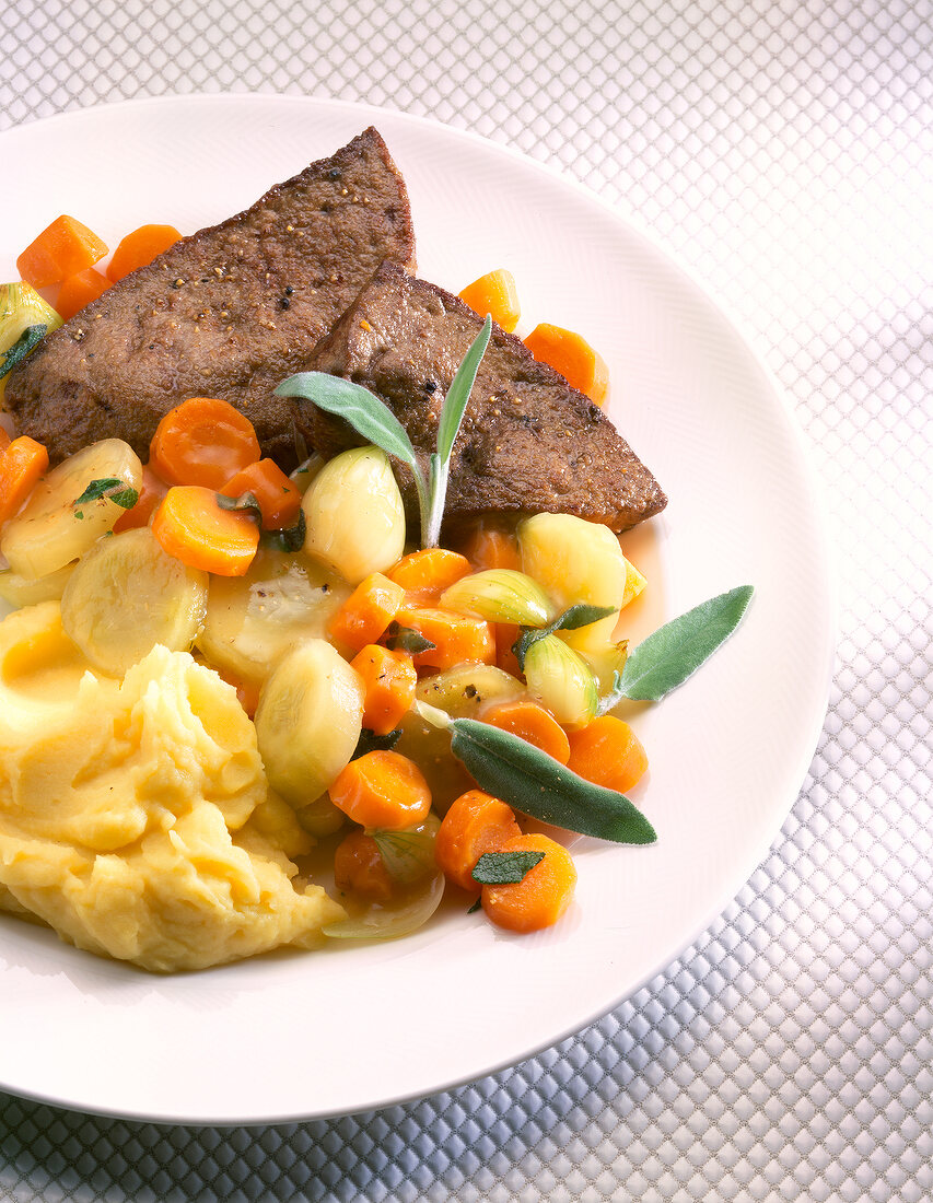 Beef liver with carrot, onion, vegetables and mashed potatoes on plate