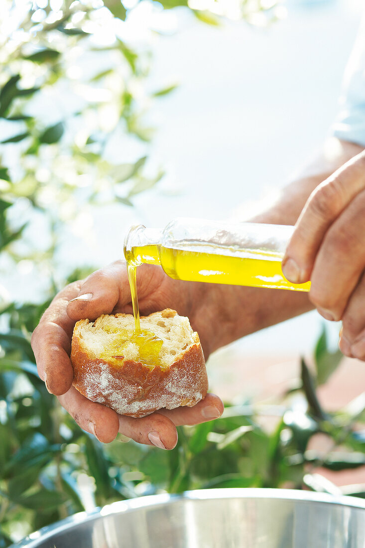 Olivenöl wird auf eine Weißbrotscheibe gegossen