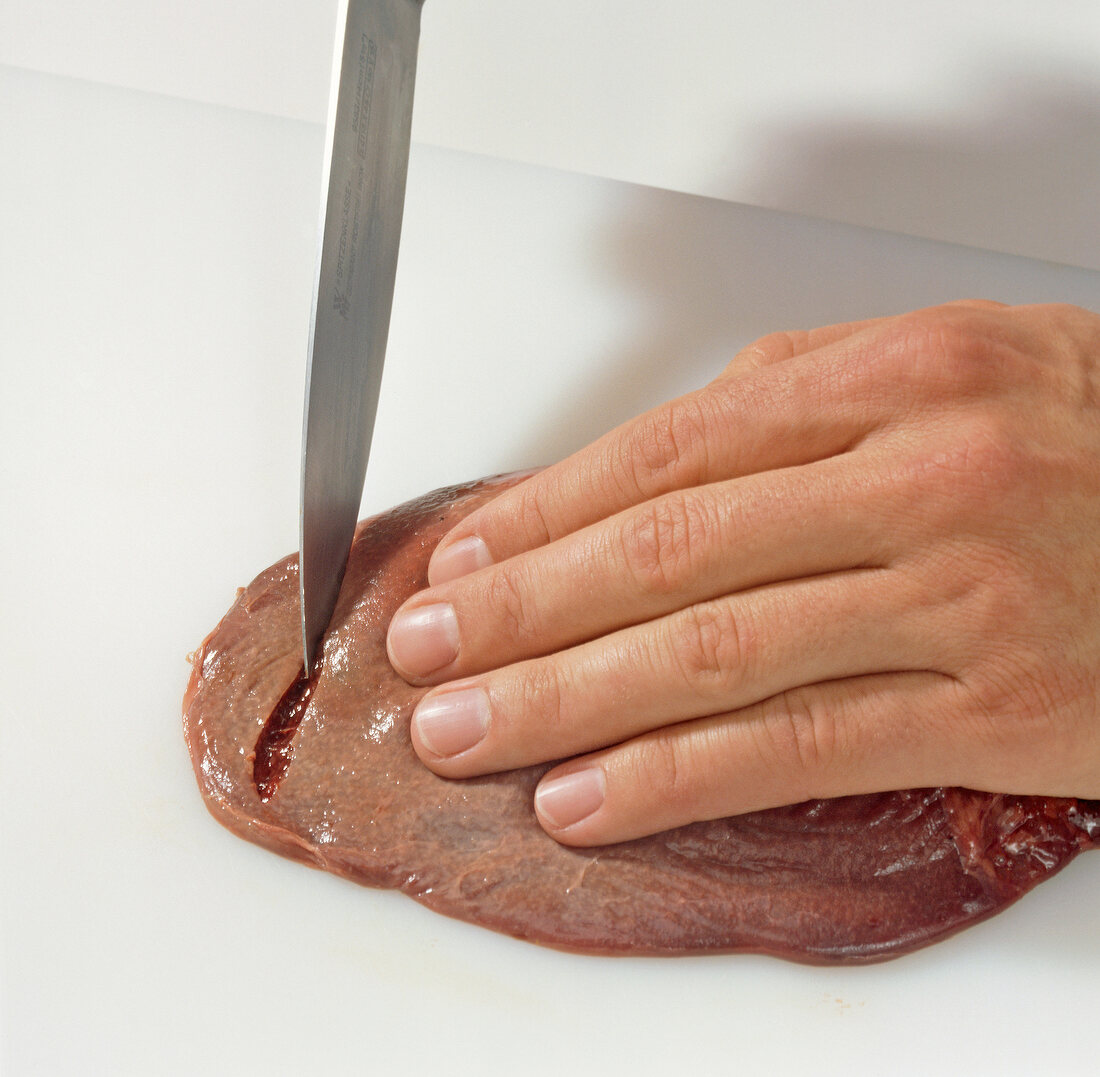 Hand cutting liver on cutting board, step 1