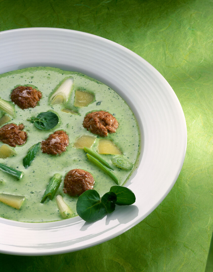 Watercress soup with meatballs on plate