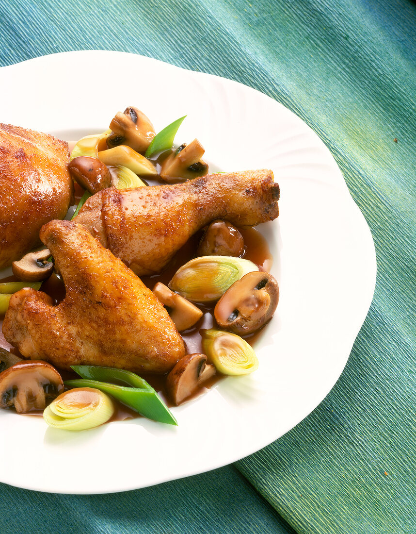 Chicken pieces with leek and mushrooms on plate