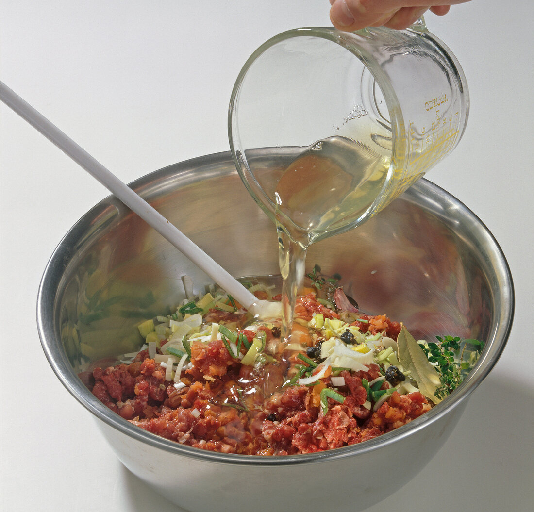 Hand pouring balsamic vinegar to mixture in bowl, step 3