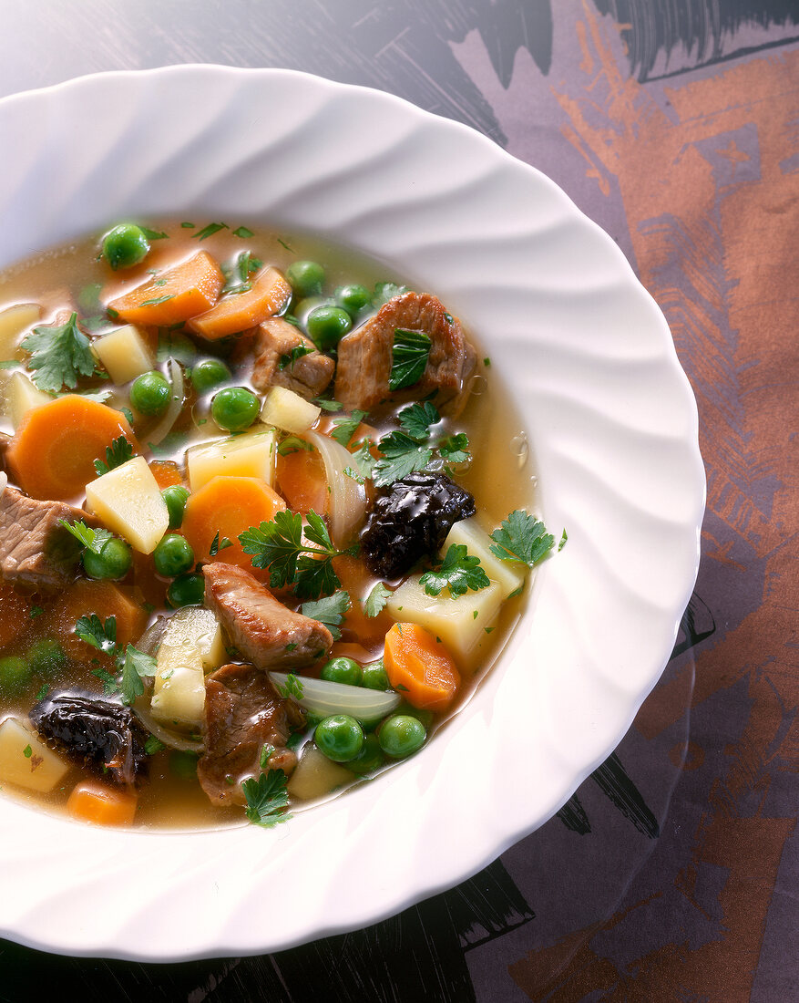 Close-up of vegetable stew with pork, carrots, potatoes and peas on plate