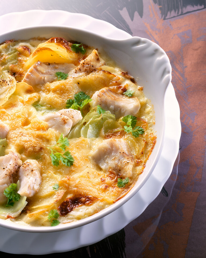 Close-up of cod fillet and vegetable bake with kohlrabi, potatoes and parsley in bowl