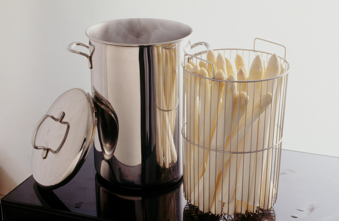 Asparagus in cylindrical colander next to cooking pot