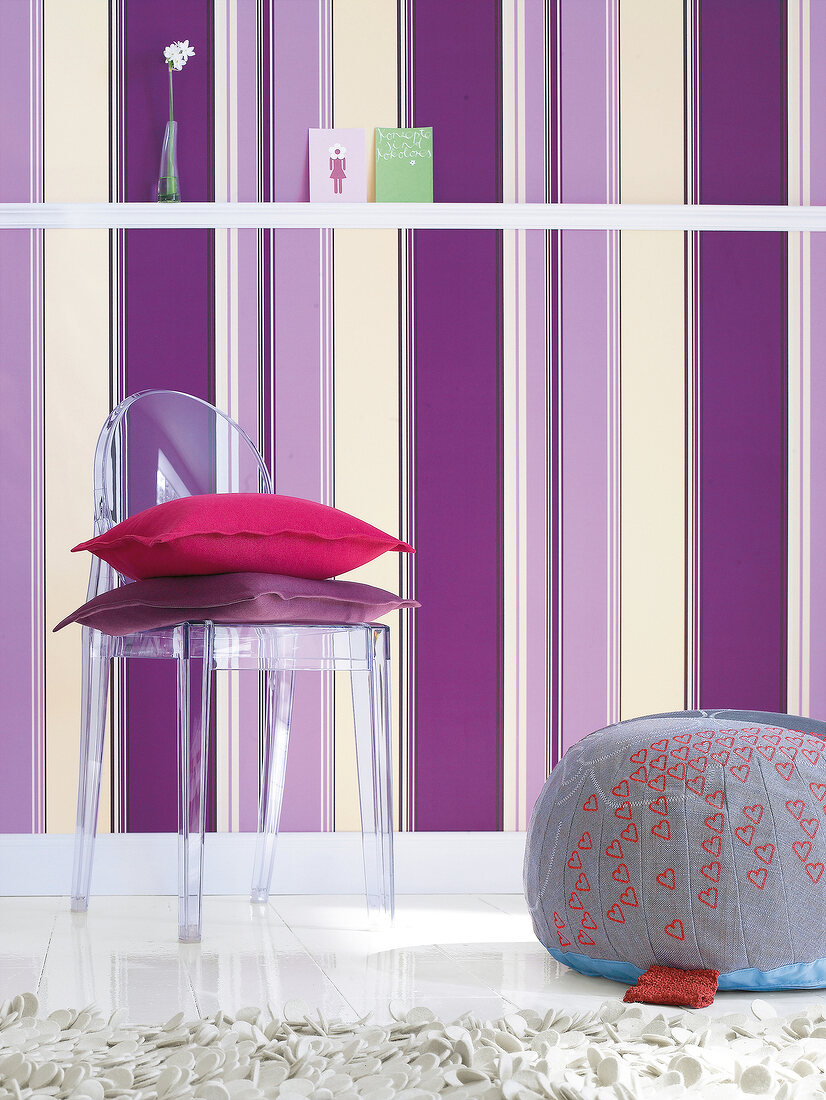 Glass chair with cushion against striped wallpaper wall
