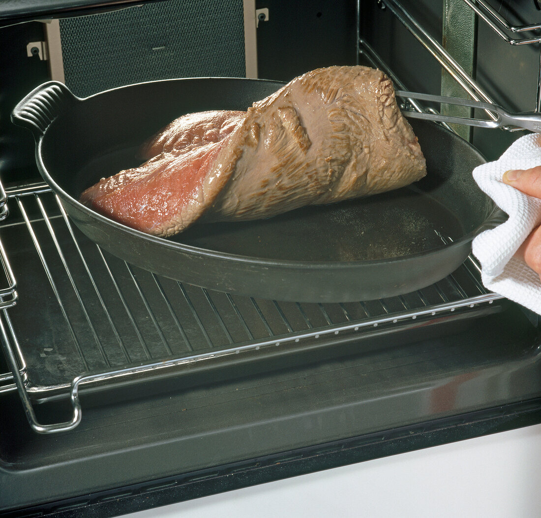 Baking dish with roast elk being placed in oven, step 1