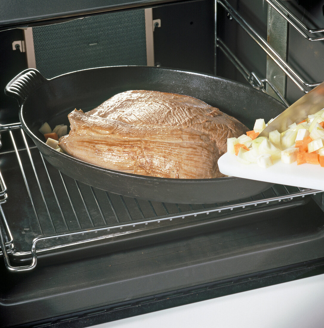 Chopped vegetables added to roast elk in baking dish, step 2