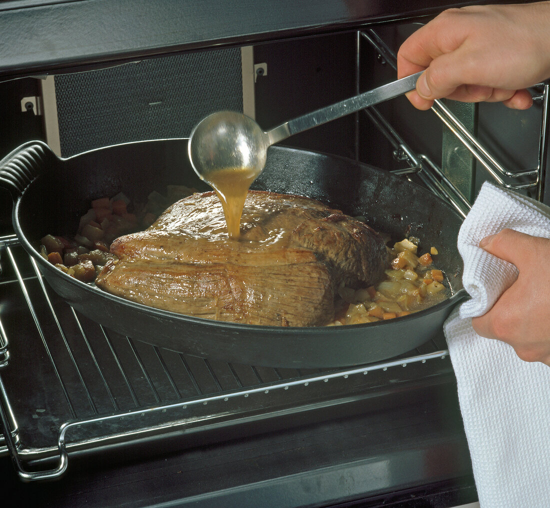 Broth being poured on roast elk in baking dish, step 4