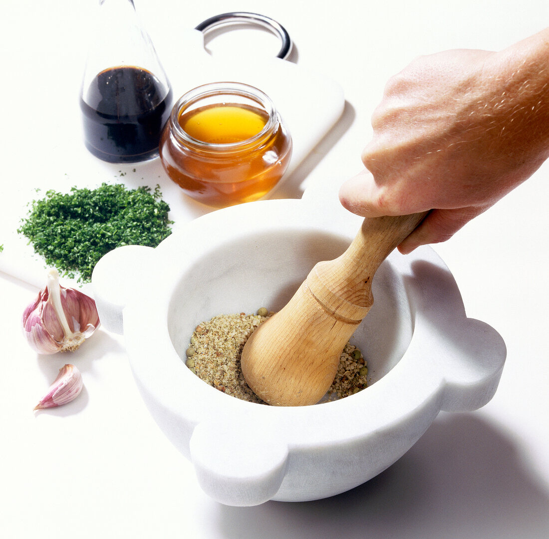 Sesame, pepper and garlic being crushed in mortal with pestle
