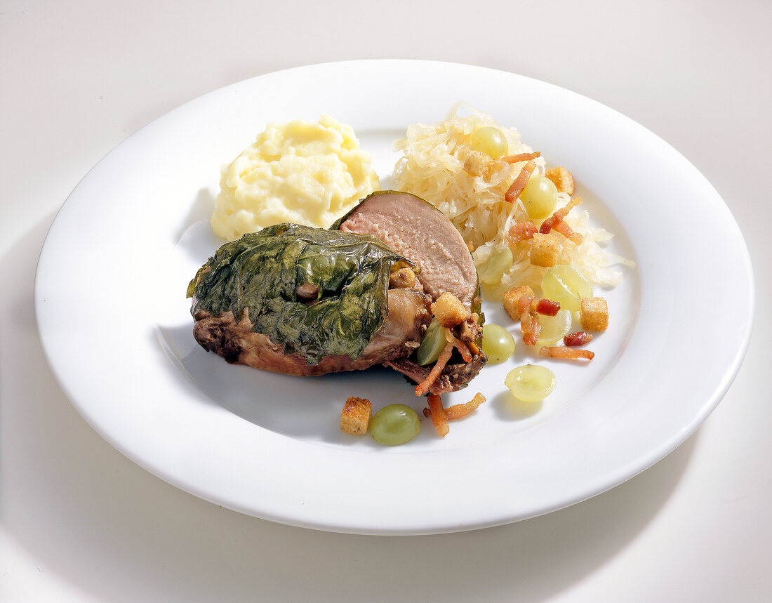 Partridge with grape leaves, sauerkraut and grapes on plate