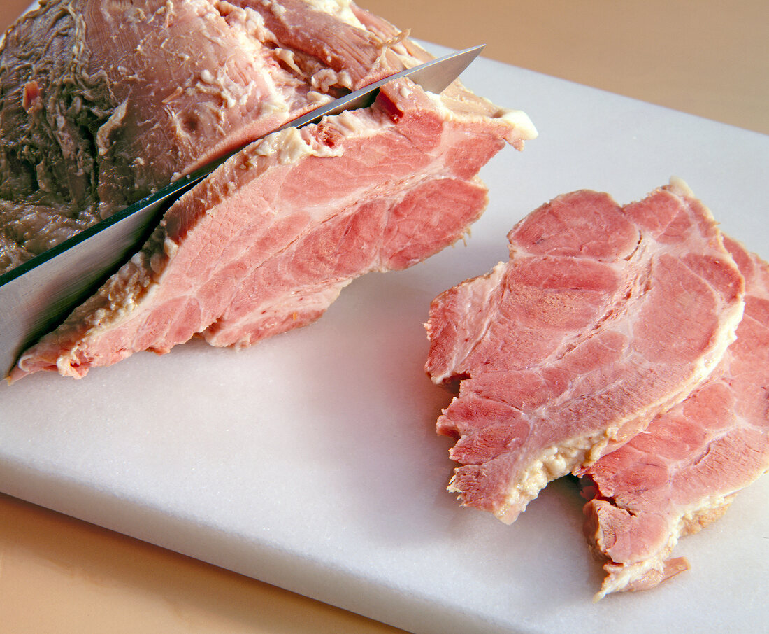 Close-up of cutting meat into slices with kitchen knife