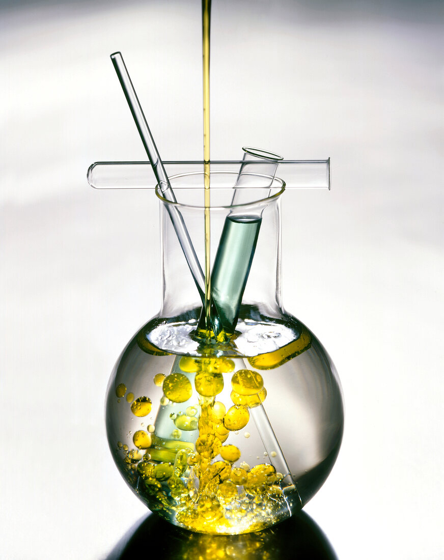 Close-up of flat bottom flask with test tubes and yellow bubbles