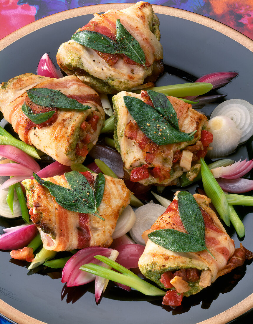 Close-up of stuffed chicken breast snacks on onions with sage leaves