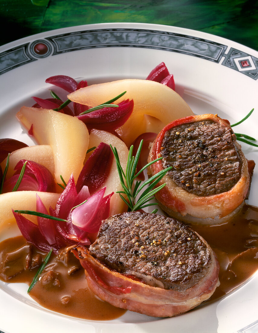Close-up of venison medallions with pears and red onions on plate
