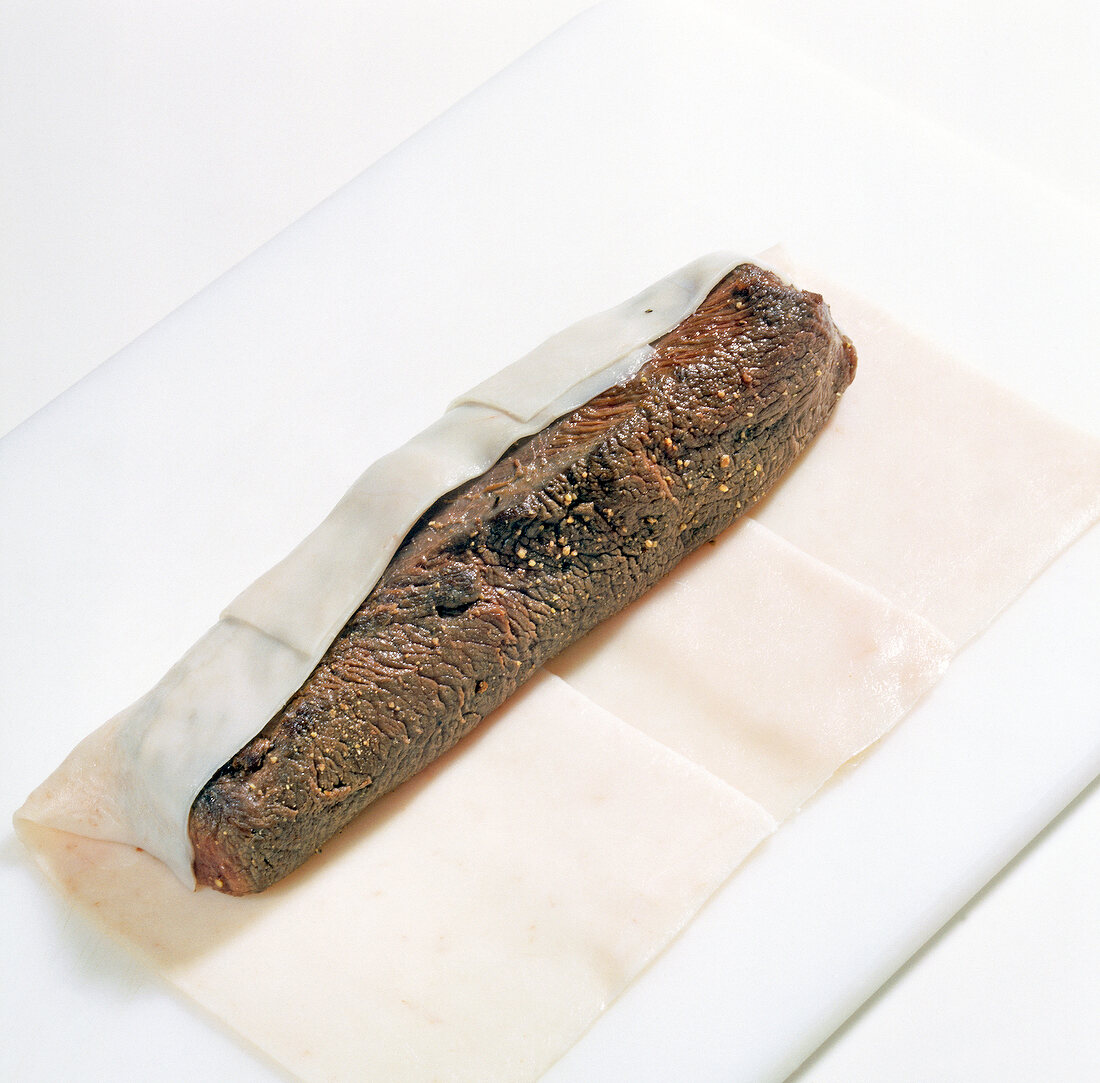 Fried mouflon meat being wrapped in dough for preparing mufflonrucken, step 2