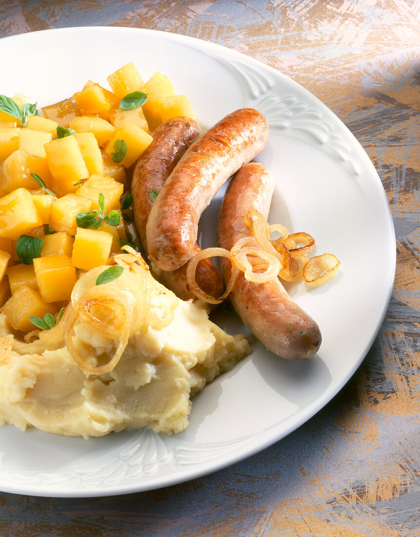 Close-up of swede vegetables with sausages, mashed potatoes and onions on plate