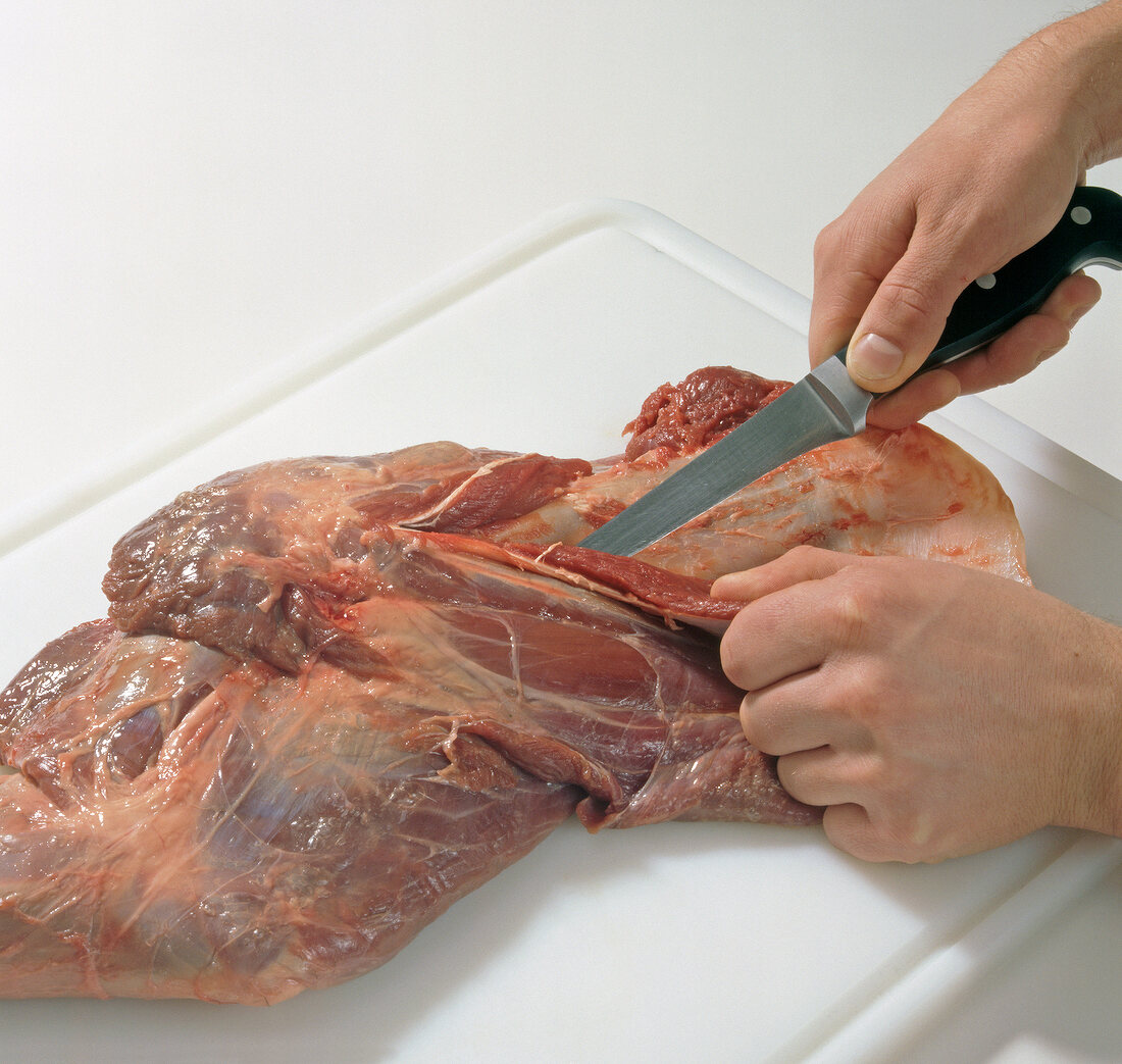 Close-up of venison being cut for preparation of braised venison, step 1