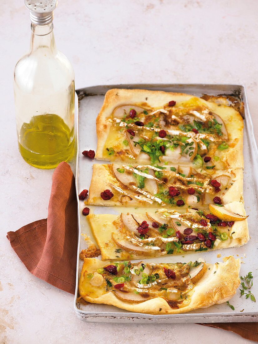 Pizza auf dem Blech mit Briekäse, Birnenscheiben, Cranberries