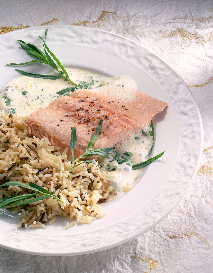 Close-up of salmon trout fillet with champagne sauce and rice on plate