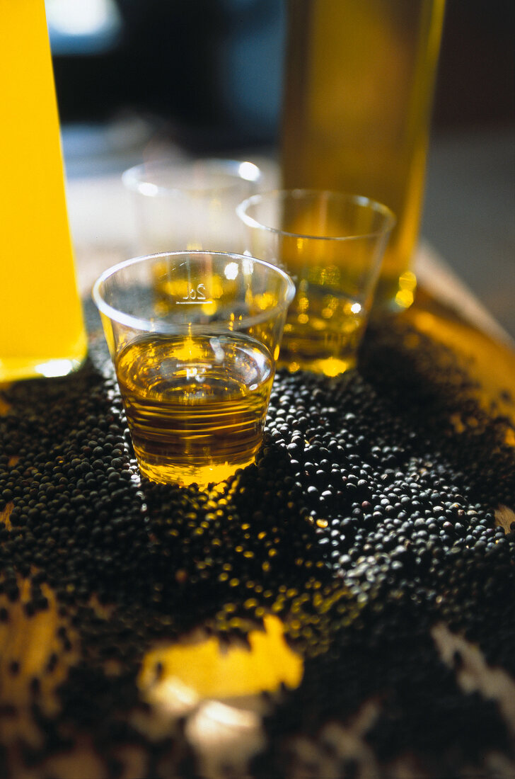 Close-up of rape seeds and canola oil in small glasses