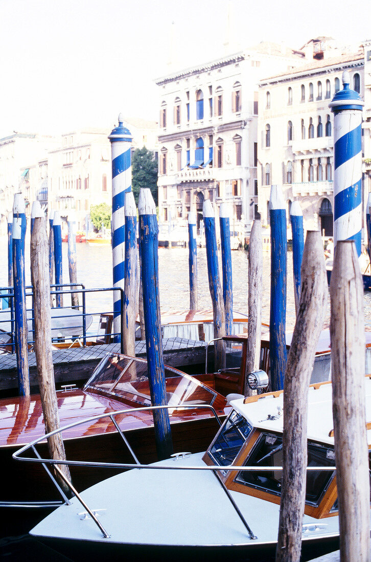 Blue wooden pillars in water around boats in Venice, Italy