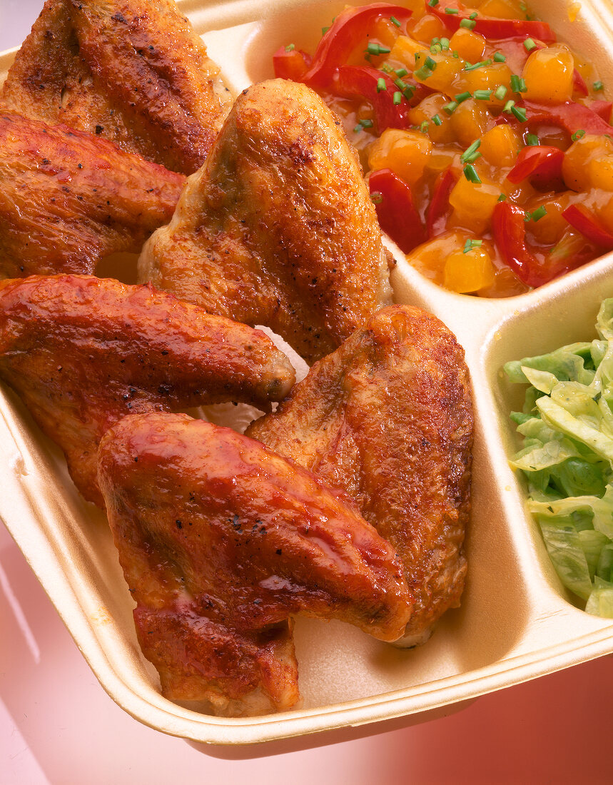 Close-up of chicken wings with salad and sauce on plate