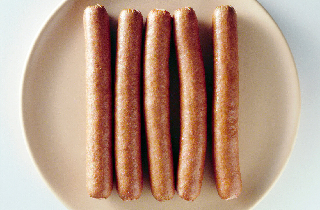 Close-up of five sausages on plate