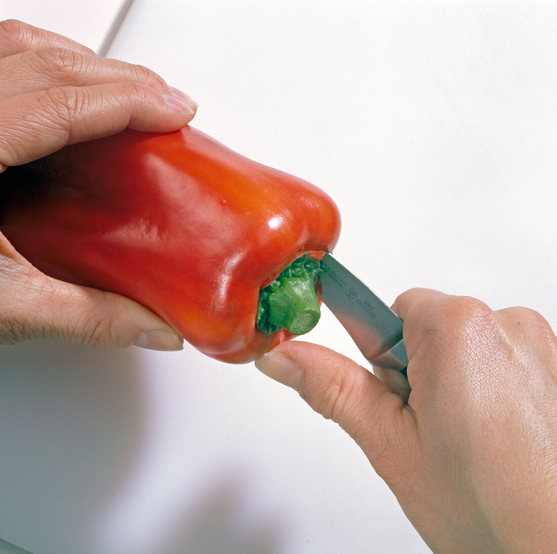 Close-up of hands cutting ends of red pepper, step 1
