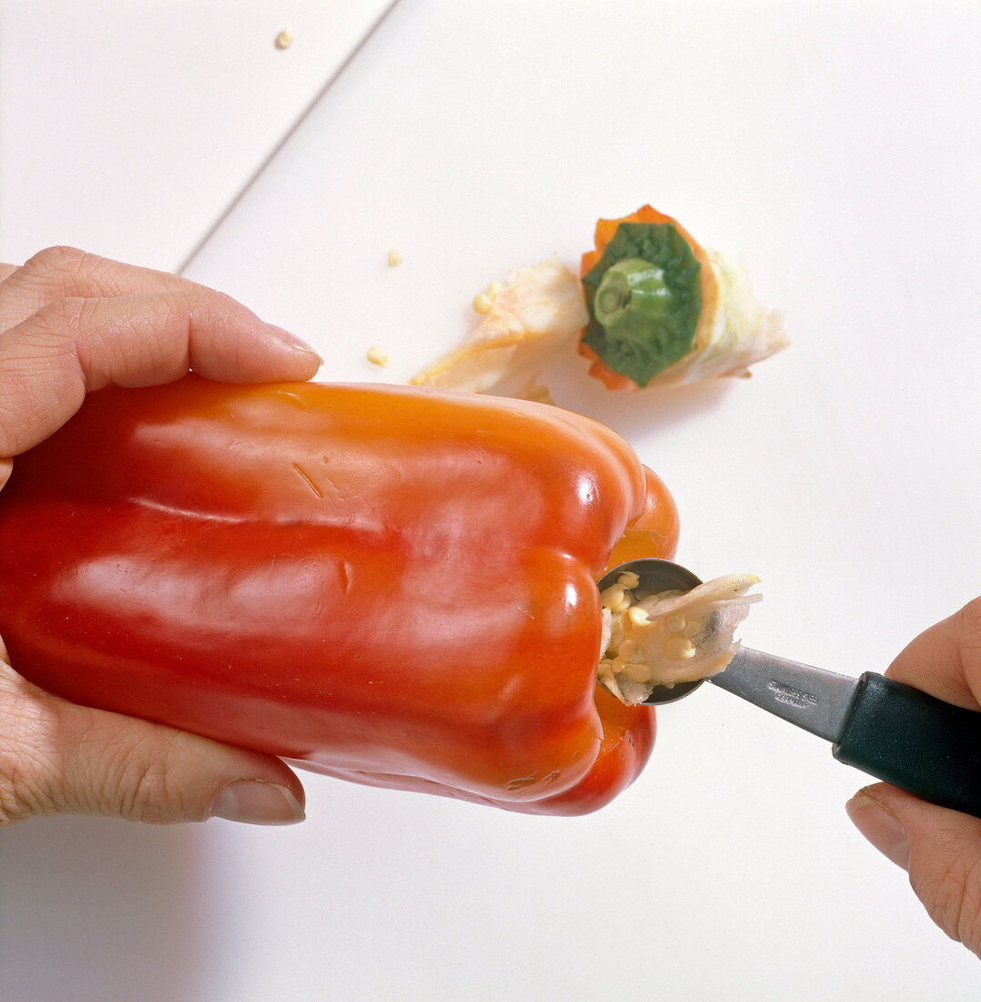 Close-up of hands removing seeds of red pepper from melon baller, step 2