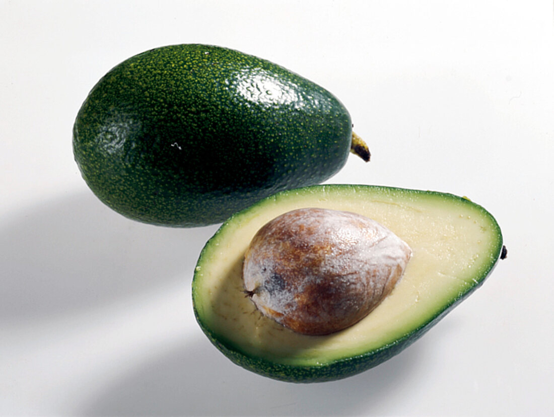 Green oval wrinkled avocados on white background