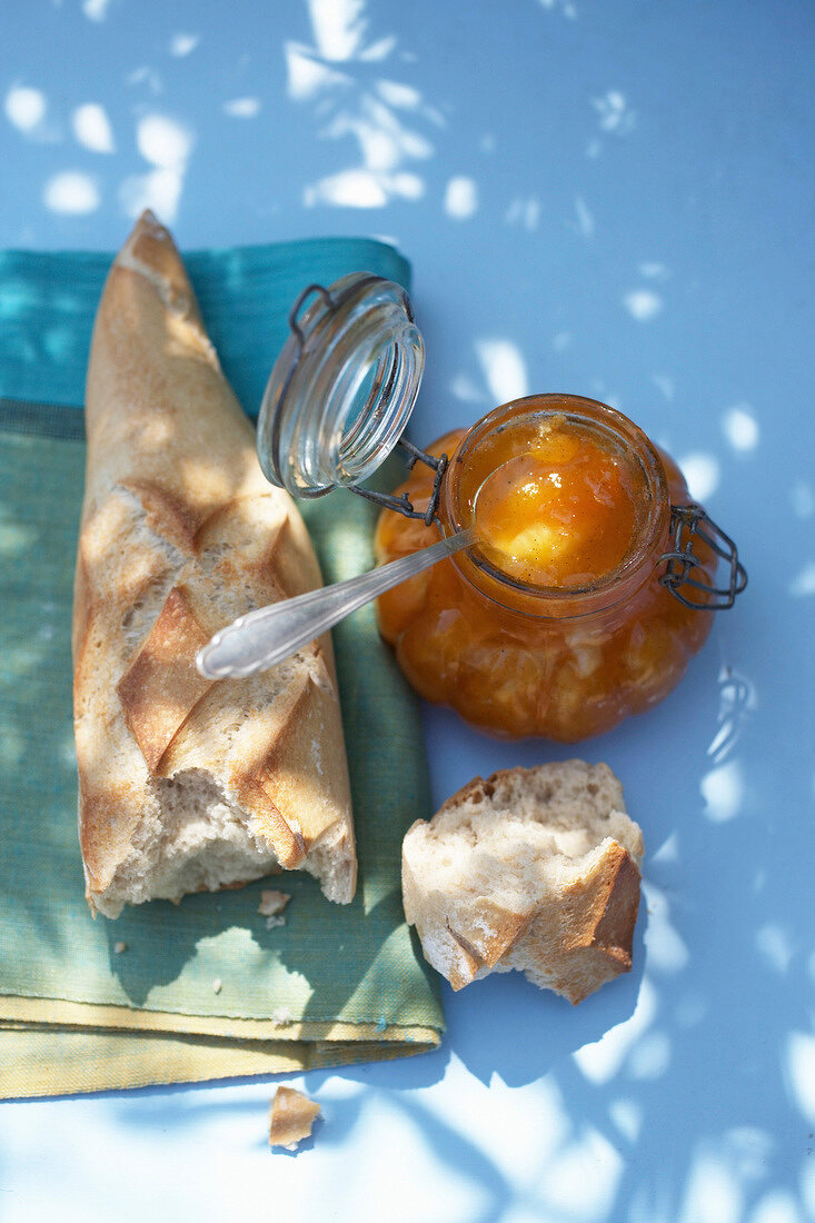 ein Glas Melonen-Aprikosen-Konfitüre mit Vanille, ein Baguette daneben