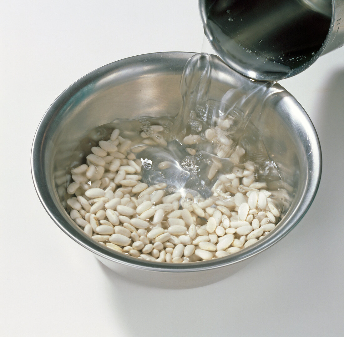 Close-up of adding water to white beans in pot, step 1